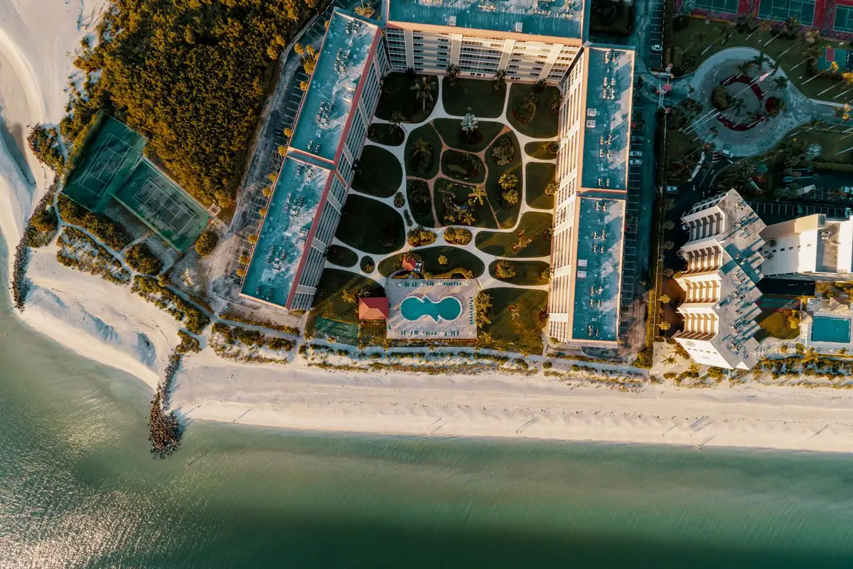 Aerial view straight down onto a beachfront resort, its pool and the Gulf shoreline
