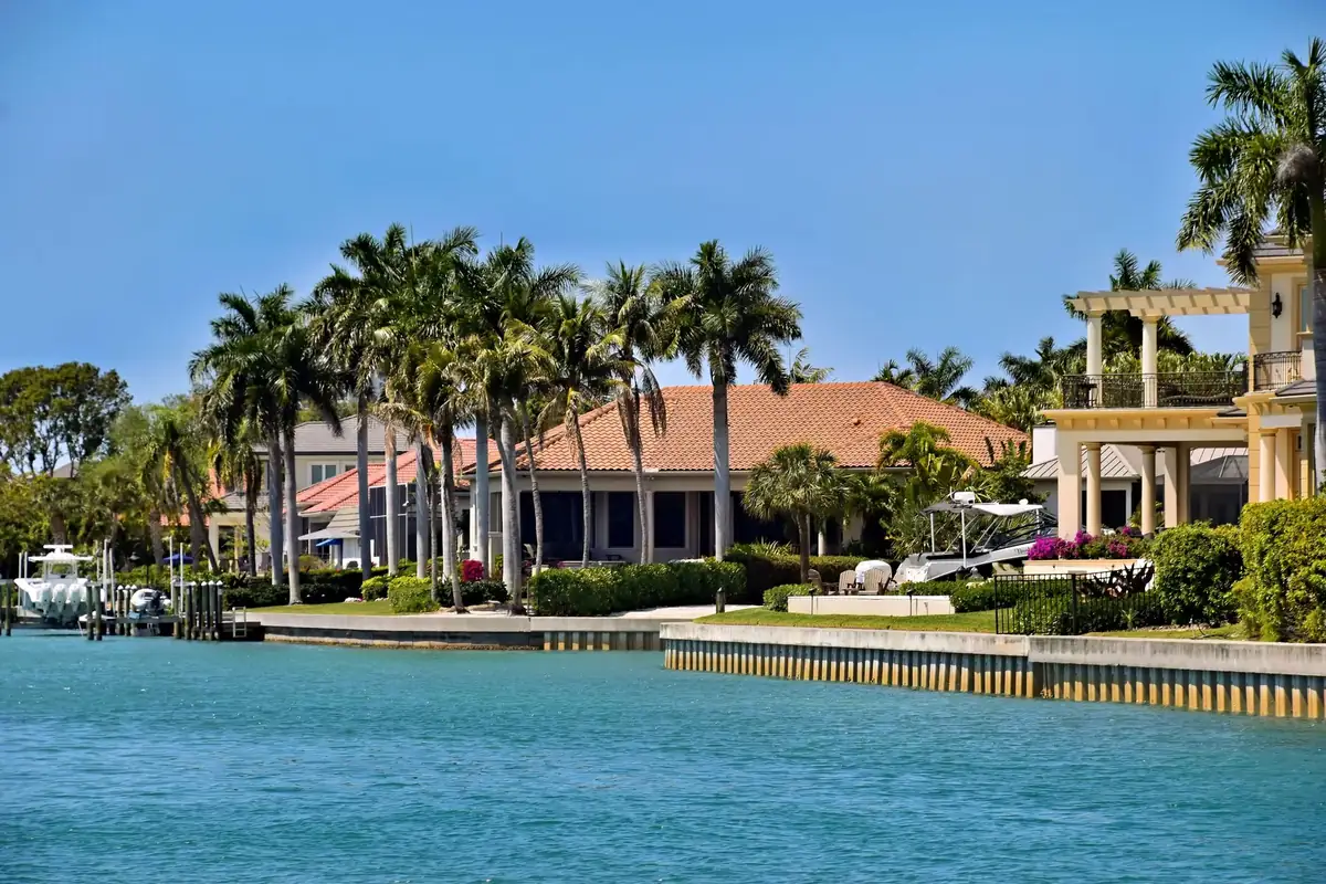 Waterfront homes behind a seawall with palm trees along a Southwest Florida waterway