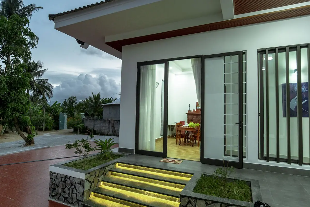 A single-story house with a wall of tall dark-framed sliding glass doors opening onto a patio